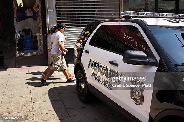 People walk by a police car in downtown on May 13, 2014 in Newark, New Jersey. Voters in New Jersey's largest city go to the polls on May 13, to...