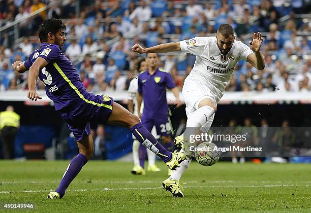 Karim Benzema of Real Madrid under pressure from Miguel Tores of Malaga during the La Liga match between Real Madrid CF and Malaga CF at Estadio...