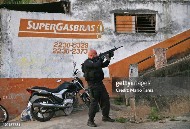 An officer from the CORE police special forces aims his weapon during an operation to search for fugitives in the Complexo do Alemao pacified...