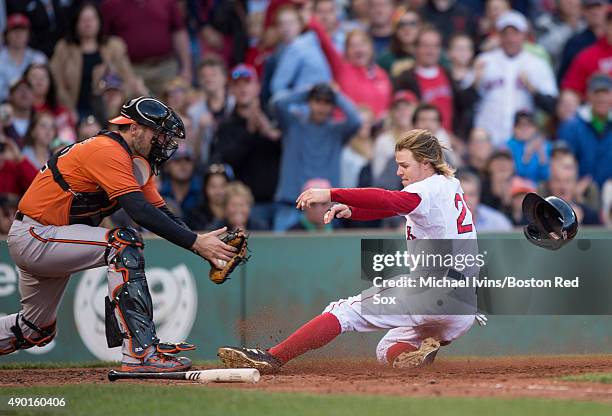 Brock Holt of the Boston Red Sox slides under the tag of Matt Wieters of the Baltimore Orioles to score a run during the fifth inning at Fenway Park...
