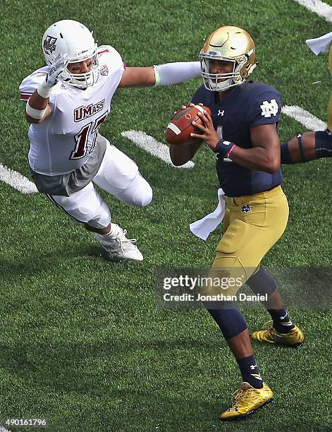 DeShone Kizer of the Notre Dame Fighting Irish looks to pass under pressure from Jovan Santos-Knox of the Massachusetts Minutemen at Notre Dame...