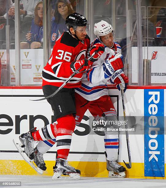 Jim O'Brien of the New Jersey Devils hits Derek Stepan of the New York Rangers into the boards during the first period during a preseason game at the...