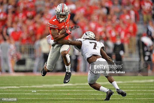 Braxton Miller of the Ohio State Buckeyes leaps to avoid the tackle attempt from Ronald Zamort of the Western Michigan Broncos in the fourth quarter...