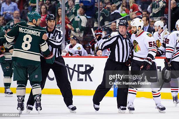 Linesmen Derek Amell and Derek Nansen separate Cody McCormick of the Minnesota Wild and Brandon Bollig of the Chicago Blackhawks in Game Four of the...