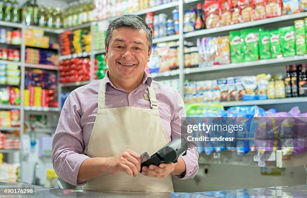 business owner holding a credit card reader - shop owner stock pictures, royalty-free photos & images