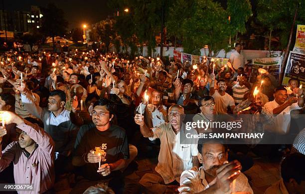 Indian members of the Patel Patidar community participate in a candlelight vigil in Ahmedabad on September 26, 2015 in memory of eight members of the...