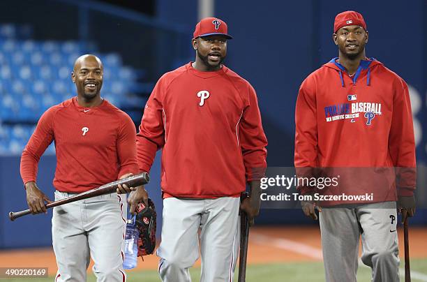 Jimmy Rollins of the Philadelphia Phillies and Ryan Howard and Domonic Brown make their way from the indoor batting cages across the field to their...