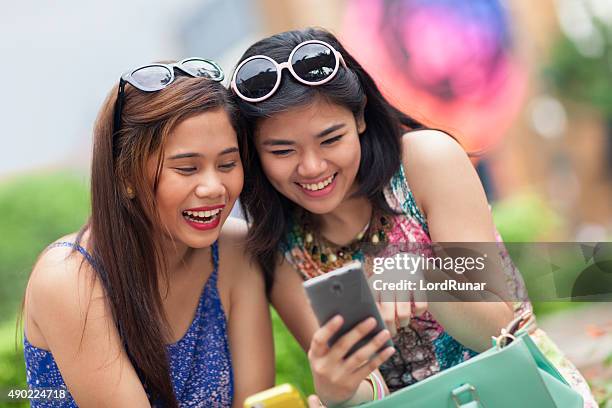 dos mujeres jóvenes divirtiéndose con un teléfono inteligente - filipinas fotografías e imágenes de stock