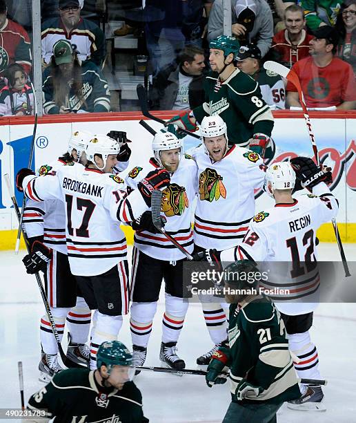 The Chicago Blackhawks celebrate a goal by Kris Versteeg as Dany Heatley, Cody McCormick and Kyle Brodziak of the Minnesota Wild looks on during the...