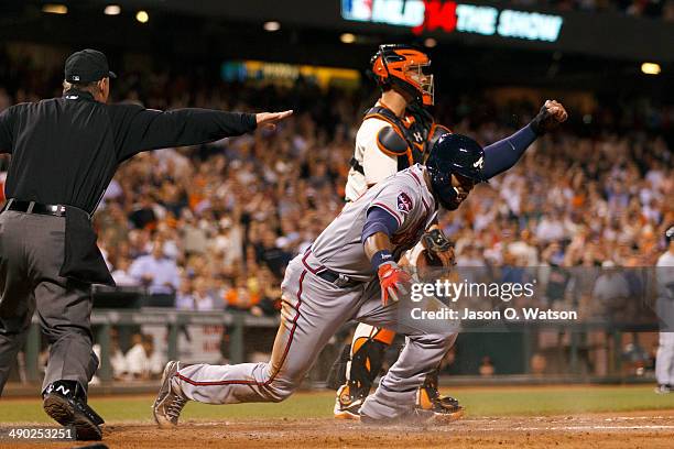 Jason Heyward of the Atlanta Braves slides into home plate to score a run past a tag from Buster Posey of the San Francisco Giants in front of umpire...