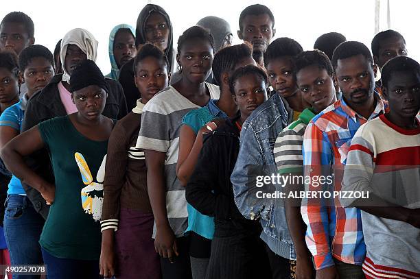 Migrants and refugees, mainly from Nigeria, Ghana, Senegal and Sierra Leone, after being rescued at sea, wait to receive food on the German navy...