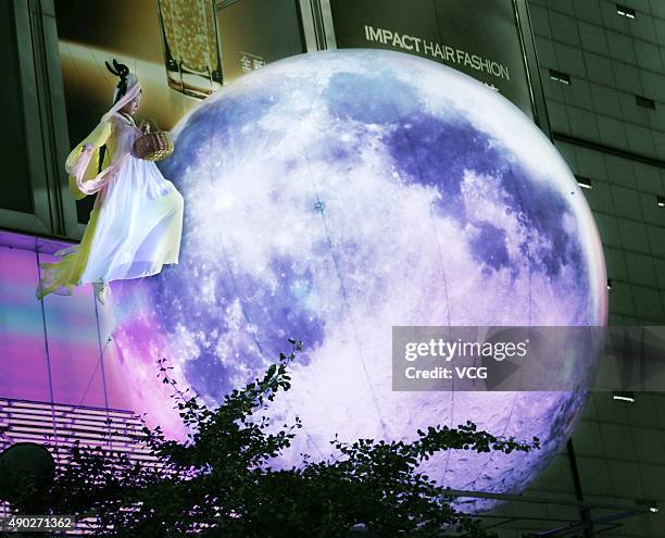 Woman dressed as Chang'e performs around a "moon" outside a shopping mall during the Mid-Autumn Festival on September 27, 2015 in Jinhua, Zhejiang...