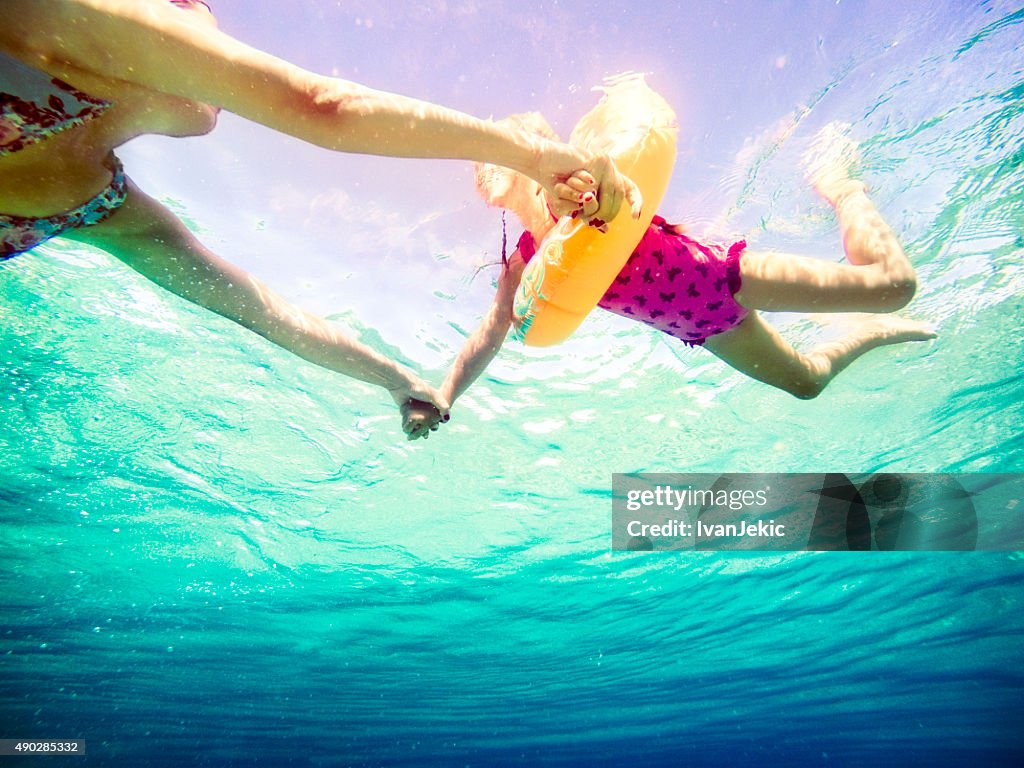 Vista subaquática de família swiming no mar e segurando as mãos