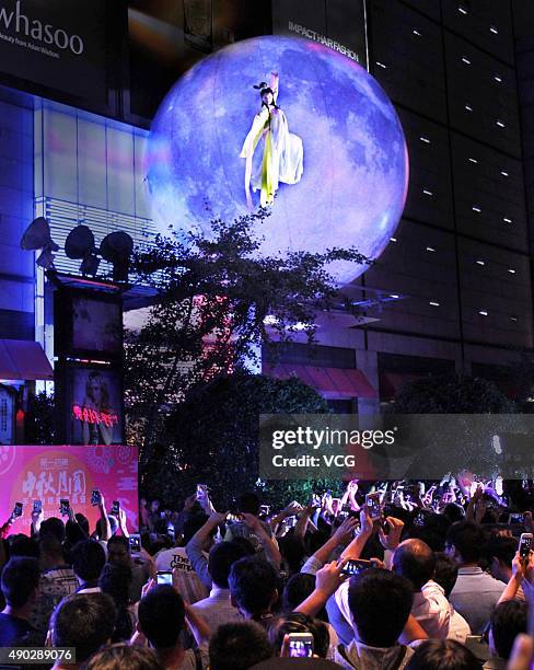 Woman dressed as Chang'e performs around a "moon" outside a shopping mall during the Mid-Autumn Festival on September 27, 2015 in Jinhua, Zhejiang...