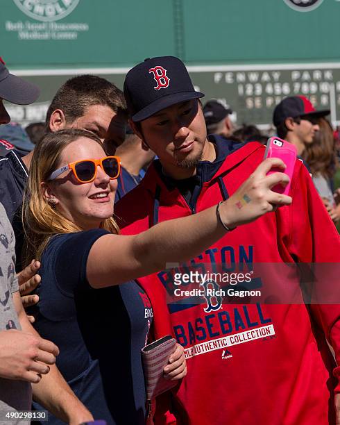 Junichi Tazawa of the Boston Red Sox poses for a photo with a fan during "Photo on the Field Day"at Fenway Park before a game against the Baltimore...