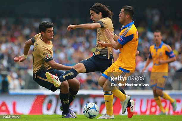Eduardo Herrera and Matias Britos of Pumas fight for the ball with Israel Jimenez of Tigres during a 10th round match between Pumas UNAM and Tigres...