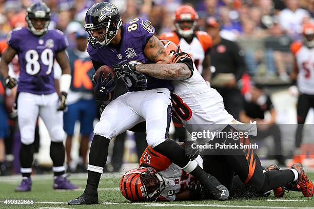 Tight end Crockett Gillmore of the Baltimore Ravens is tackled by middle linebacker Rey Maualuga of the Cincinnati Bengals and outside linebacker...