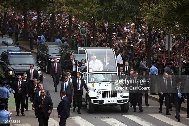Pope Francis waves as he drives along Benjamin Franklin Parkway to lead Mass on September 27, 2015 in Philadelphia, Pennsylvania. Pope Francis is on...