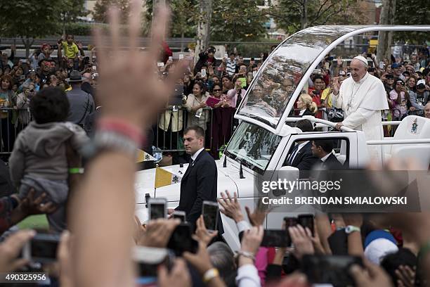 Pope Francis gestures while traveling to a mass celebrated for the World Meeting of Families on Benjamin Franklin Parkway September 27, 2015 in...