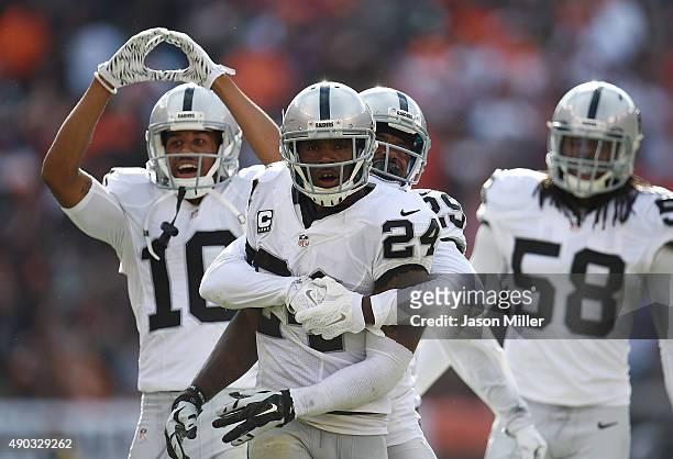 Charles Woodson of the Oakland Raiders celebrates with David Amerson after intercepting a pass during the fourth quarter against the Cleveland Browns...