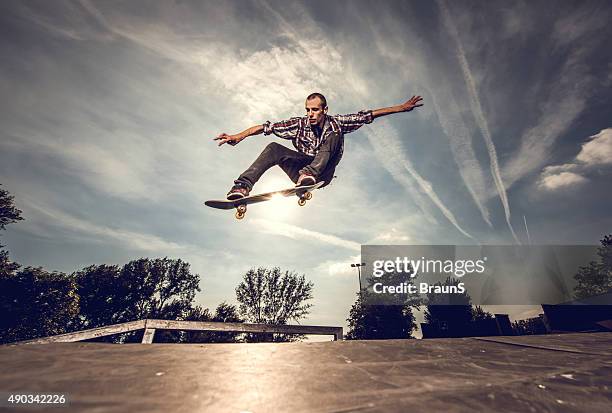 low angle view of a young man skateboarding outdoors. - extreme skating stock pictures, royalty-free photos & images