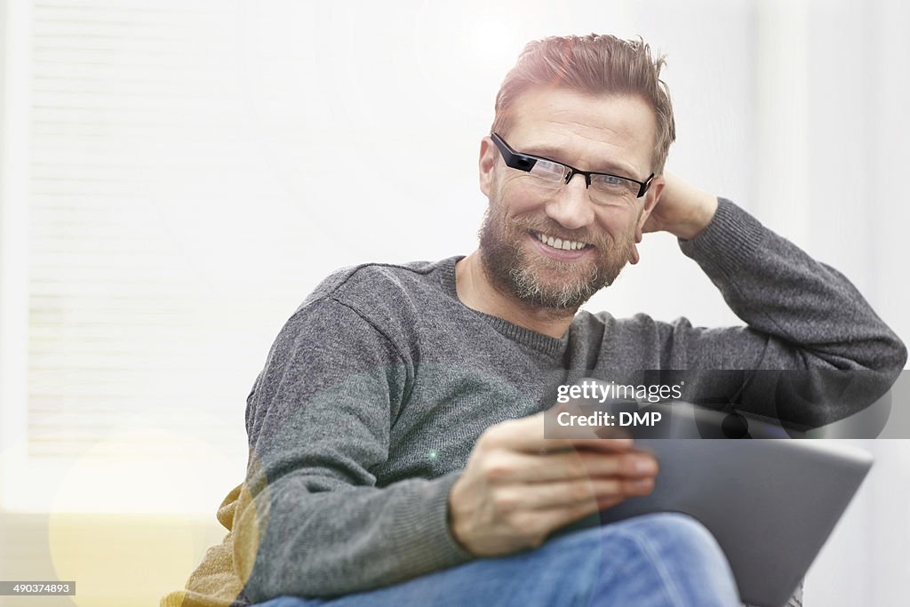 Young man wearing smart glasses with tablet at home