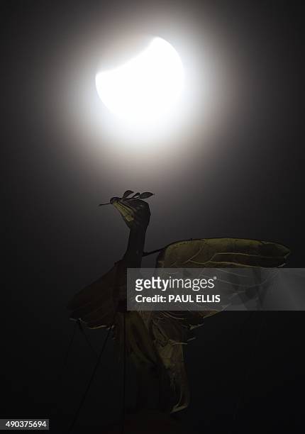The moon starts to eclipse as it rises above the iconic Liver Bird on the Liver Building in Liverpool, north west England, early on September 28,...
