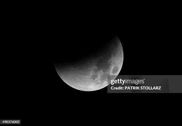 The start of total lunar eclipse to a blood moon is seen in the dark sky in Essen, western Germany, on September 28, 2015. AFP PHOTO / PATRIK STOLLARZ