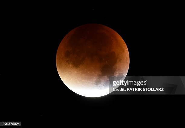 The start of total lunar eclipse to a blood moon is seen in the dark sky in Essen, western Germany, on September 28, 2015. AFP PHOTO / PATRIK STOLLARZ