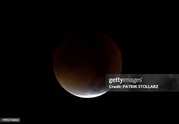 The start of total lunar eclipse to a blood moon is seen in the dark sky in Essen, western Germany, on September 28, 2015. AFP PHOTO / PATRIK...