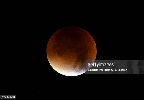 The start of total lunar eclipse to a blood moon is seen in the dark sky in Essen, western Germany, on September 28, 2015. AFP PHOTO / PATRIK STOLLARZ