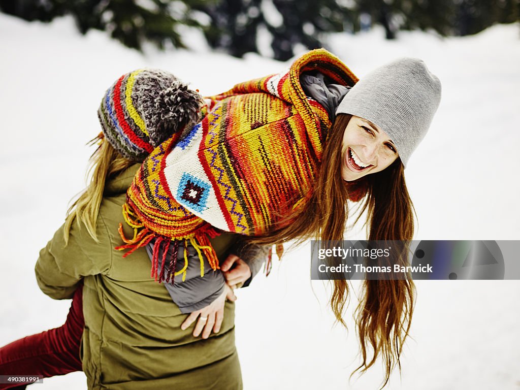 Woman carrying female friend over shoulder