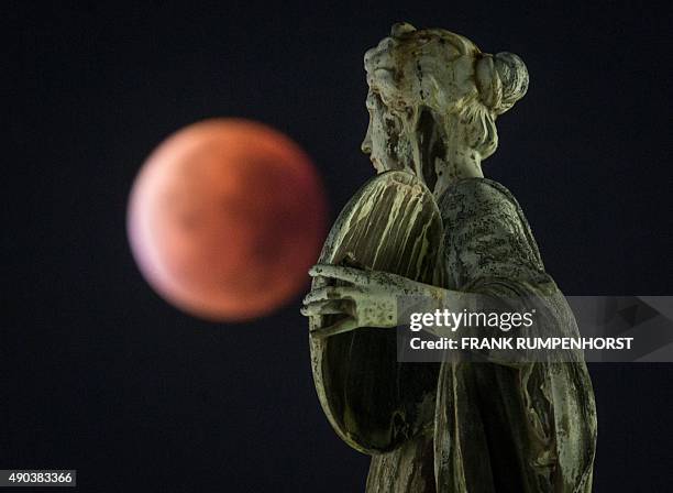 So-called "blood moon" can be seen behind a statue during a total lunar eclipse in Frankfurt am Main, western Germany, on September 28, 2015....