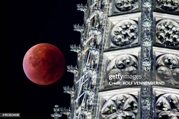 So-called "blood moon" can be seen behind one of the steeples of the Cologne Cathedral during a total lunar eclipse in Cologne, western Germany, on...