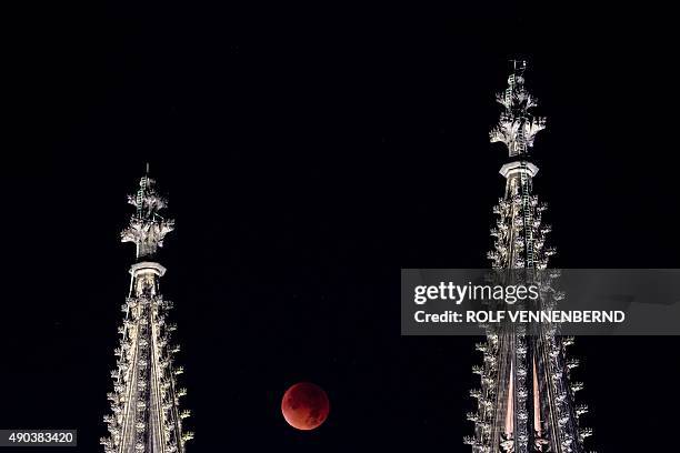 So-called "blood moon" can be seen between the steeples of the Cologne Cathedral during a total lunar eclipse in Cologne, western Germany, on...