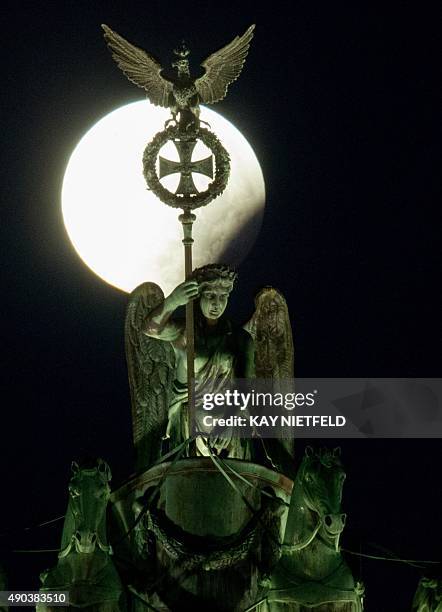 So-called "super moon" can be seen behind the Quadriga sculpture on top of Berlin's landmark the Brandenburg Gate during a total lunar eclipse on...