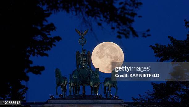 So-called "super moon" can be seen behind the Quadriga sculpture on top of Berlin's landmark the Brandenburg Gate at the beginning of a total lunar...