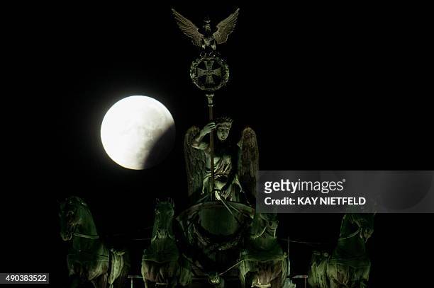 So-called "super moon" can be seen behind the Quadriga sculpture on top of Berlin's landmark the Brandenburg Gate during a total lunar eclipse on...