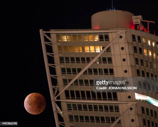The so-called supermoon appears behind the Turning Torso building in Malmo in the south of Sweden during a total lunar eclipse on September 28, 2015....