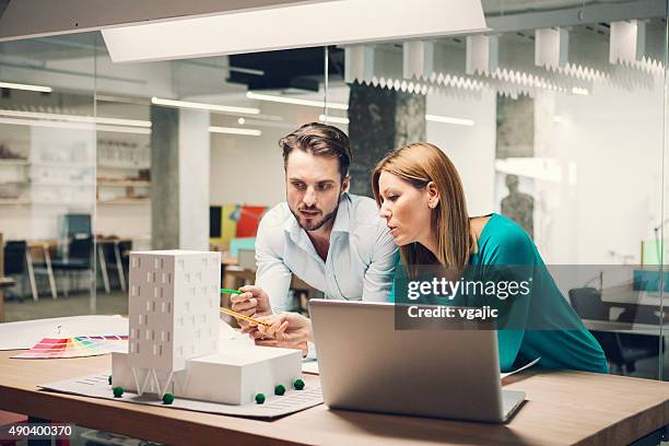 los diseñadores revisar modelo arquitectónico en la oficina. - architect fotografías e imágenes de stock