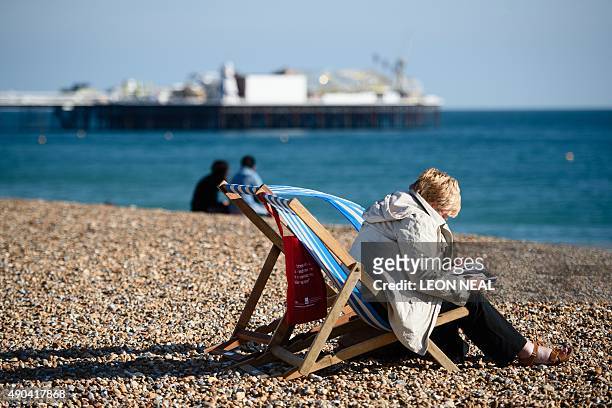 Conference delegate sits on a deck chair on the beach as Brighton Pier is seen in the backround on a sunny day on day two of the annual Labour party...