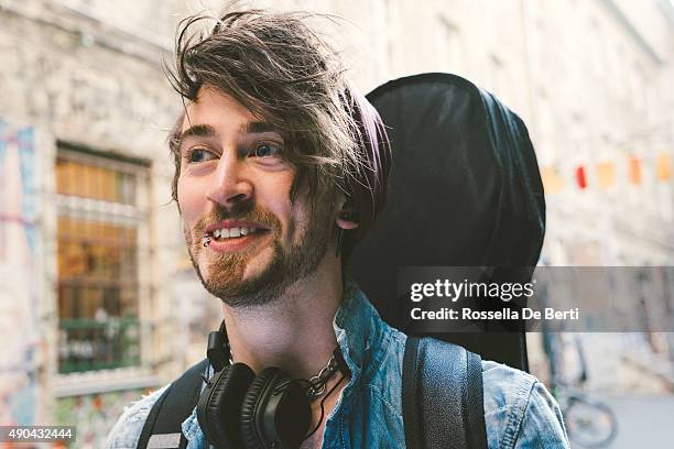 ritratto di un musicista che cammina lungo la strada - custodia per chitarra foto e immagini stock