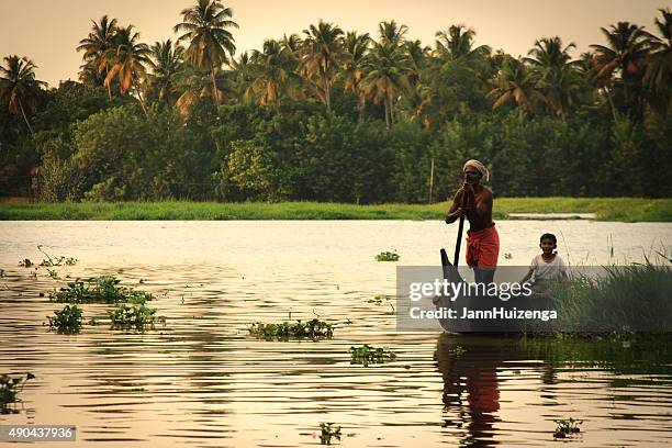 kerala, india: fisherman, child, and canoe in kerala backwaters - malabar_coast stock pictures, royalty-free photos & images