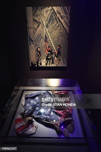 An American flag found at the World Trade Center site and a photograph of a flag raising at the site by Thomas E. Franklin/The Record , seen during a...