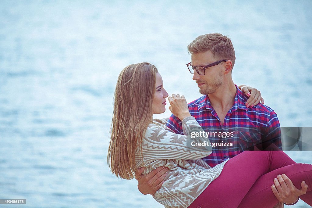 Young loving couple by the waterfront at beautiful autumn day