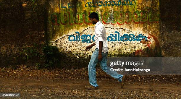 kochi (kerala), indien: junger mann zu fuß vorbei an farbenfrohen wand - daily life in kerala stock-fotos und bilder