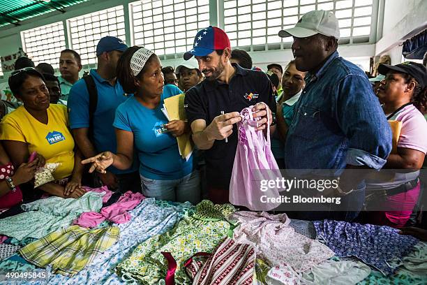 Henrique Capriles, governor of the state of Miranda and a former presidential candidate in the last two elections, center, looks at clothing made by...