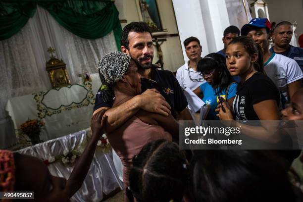 Henrique Capriles, governor of the state of Miranda and a former presidential candidate in the last two elections, center, embraces an elderly woman...