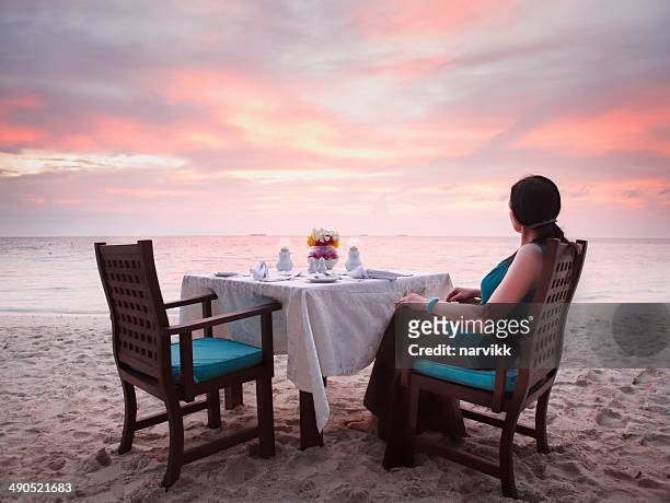 woman sitting on the beach by romantic sunset - romantic dining stock pictures, royalty-free photos & images