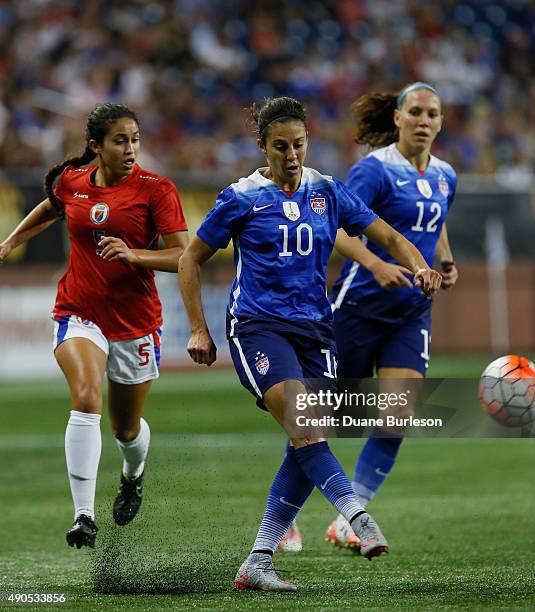 Carli Lloyd of the United States takes a shot on goal while being pursued by Sabine Chandler of Haiti as Lauren Holiday of the United States looks on...